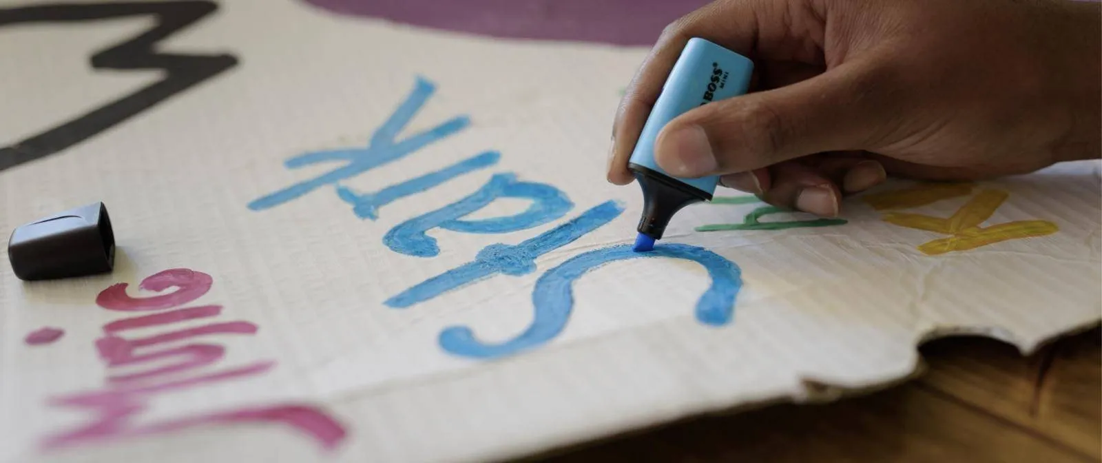 Eine Hand schreibt mit einem Marker auf Pappe